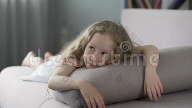 嬉戏的<strong>小女孩躺在</strong>家里的<strong>沙发上</strong>，满脸笑容地等待着父母